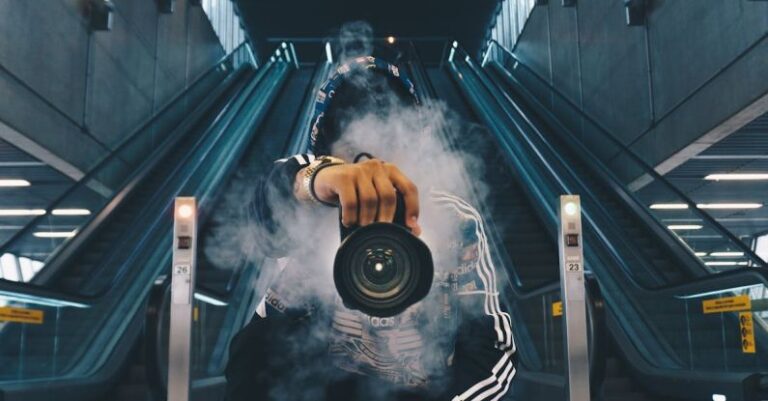 Photography - Man Holding Camera While Squating With Smoke on Face Inside Building