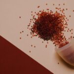 Bleed - Top view of silicone menstrual cup with red beads scattered on pink surface