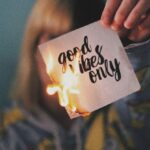 Paper Finish - Unrecognizable female showing burning paper with written inscription and bright flame on blurred background