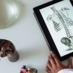 Coated Paper - Unrecognizable African American scientist studying anatomy with tablet