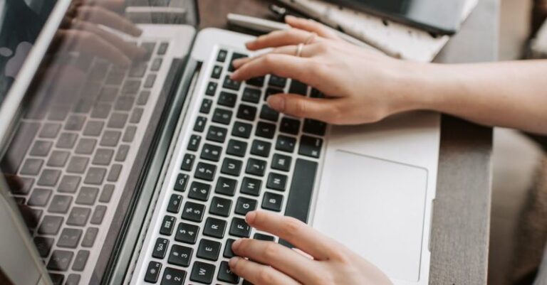 Digital Flipbooks - From above of unrecognizable woman sitting at table and typing on keyboard of computer during remote work in modern workspace